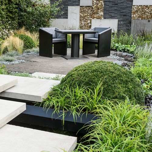 Large square bistro table with grey accents Ironfire Furniture's Bistro table presented in a landscaped garden